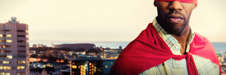 Man pretending to be a superhero against illuminated buildings by road in cityの写真素材