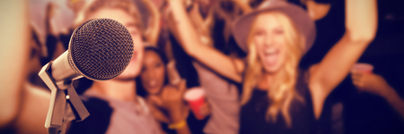 Microphone with stand against portrait of friends dancing in clubの写真素材