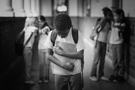 Sad pupil being bullied by classmates at corridor in schoolの写真素材