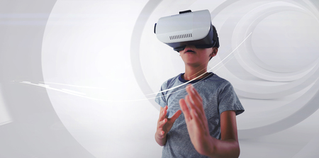 Boy gesturing while using virtual reality headset against white background