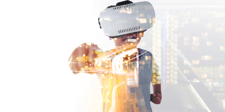 Smiling boy wearing virtual headset playing against white background