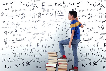 Boy climbing books against mathsの写真素材