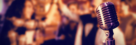 Close-up of microphone  against friends doing high five in clubの写真素材