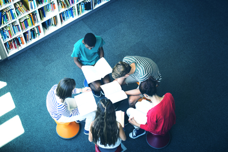 Overhead view of attentive students studying in library at schoolの写真素材