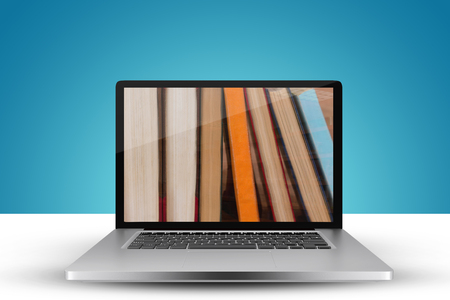 Laptop with with screen against various book on wooden tableの写真素材