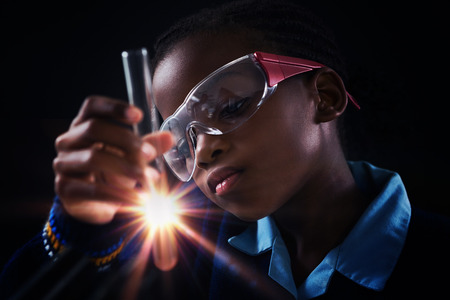 Attentive schoolgirl doing a chemical experiment against black backgroundの写真素材