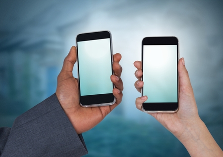 Digital composite of phones in two hands illuminatedの写真素材