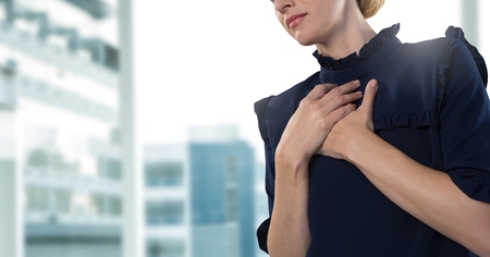 Digital composite of Businesswoman holding chest in office