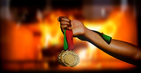 Digital composite of Champion sports medal and burning fire