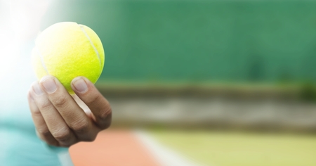 Digital composite of Hand holding tennis ball on courtの写真素材