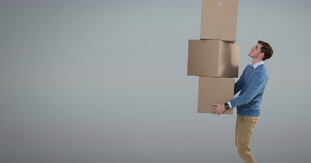 Digital composite of Man holding delivery boxes with grey background