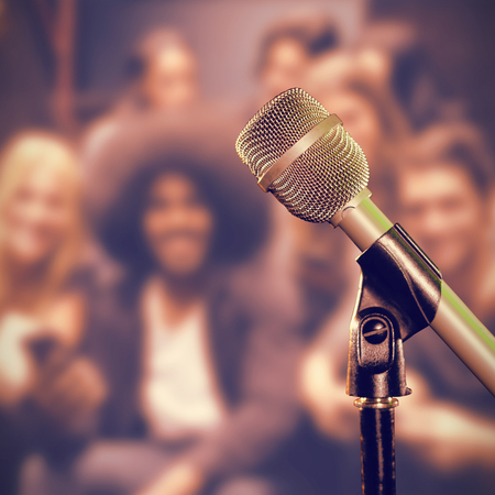 Close-up of microphone against smiling friends using mobile phones on stepsの写真素材