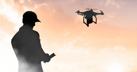 Digital composite of Man flying a drone silhouette in sky