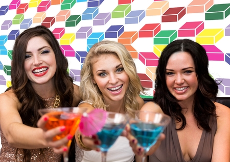 Digital composite of Fun women friends holding cocktails with colorful geometric pattern