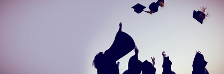Five graduates throwing their hats against clear skyの写真素材