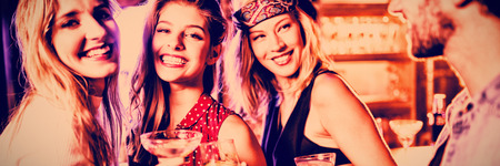 Women with male friend standing at counter in nightclubの写真素材