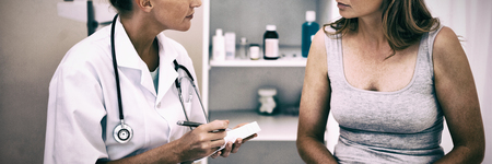 Doctor taking notes while patient is talkingの写真素材