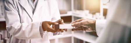 Cropped image of patient hand taking box from pharmacist at pharmacyの写真素材