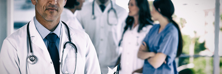 Mature doctor pointing seriously at something on his clipboard
