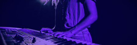 Mid section of female musician playing piano in illuminated nightclubの写真素材