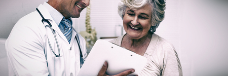Happy doctor and patient discussing over reports in clinicの写真素材