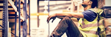 Tired manual worker sitting on floor in warehouseの写真素材