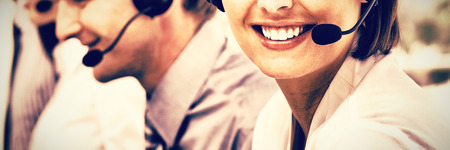 Female customer service agent with headset on in a call centerの写真素材