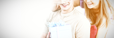 Smiling woman giving a present to her boyfriend in the livingroomの写真素材