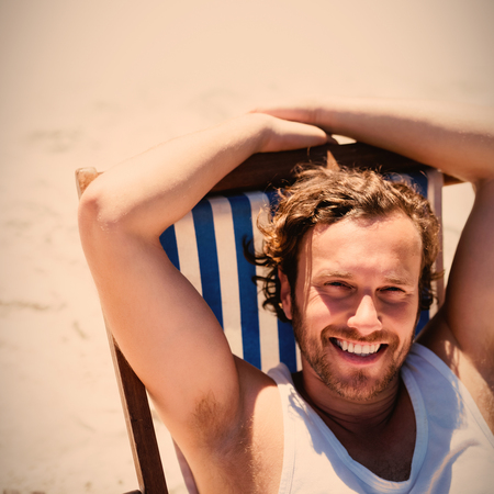 High angle portrait of young woman relaxaing on lounge chair at beach during sunny dayの写真素材