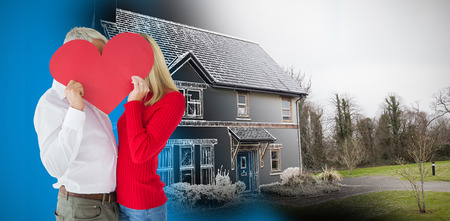 Couple embracing and holding heart over faces against home sketchの写真素材