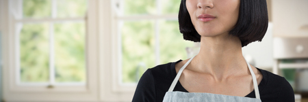 Waitress standing against white background against empty kitchen with vegetables and mixer
