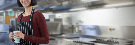 Smiling waitress holding coffee against white background against picture of restaurant kitchen