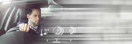 Digital composite of Man driving in car with heads up display interface and motion transition