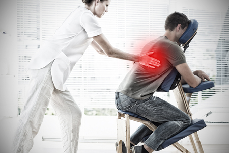 Highlighted pain against therapist massaging patient backの写真素材