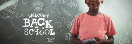 back to school against smiling boy holding cellphone against greenboard