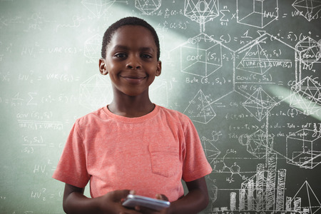 Maths against smiling boy holding cellphone against greenboard