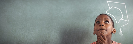 Graduation hat vector against thoughtful boy against greenboard in classroomの写真素材