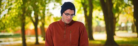 Man standing with hands in pocket against defocused image of trees growing at park