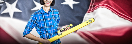 Female architect holding measuring equipment against grey background against close-up of american...