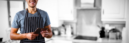 Male waiter holding digital tablet against view of a kitchenの写真素材