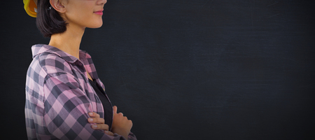 Female architect standing with arms crossed against white background against black backgroundの写真素材