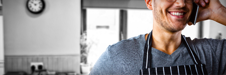 Male waiter talking on mobile phone against view of kitchenの写真素材
