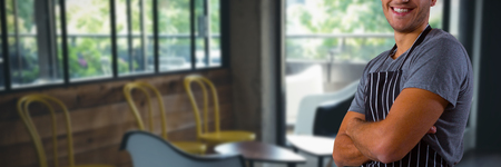Male waiter standing with arms crossed against chairs and table in officeの写真素材