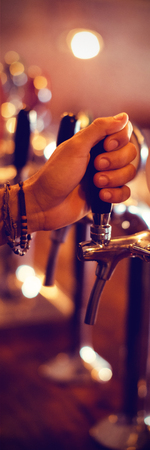 Close-up of bartender hands using beer tap in pubの写真素材