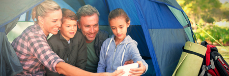 Smiling family taking a selfie in the tent at campsite