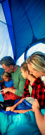 Family reading book together in the tentの写真素材