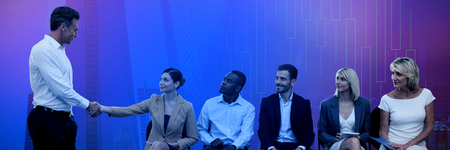 Businessman giving handshake to colleague sitting on chair against stocks and sharesの写真素材