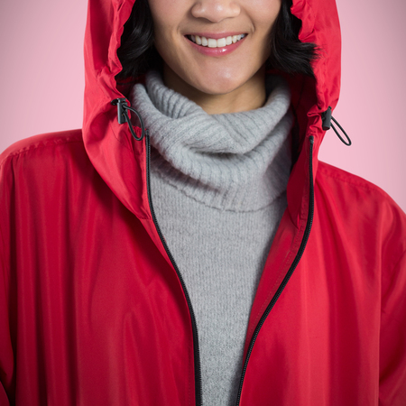 Smiling woman in hooded jacket standing against white background against pink background