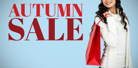 Woman with christmas hat holding red shopping bag against blue backgroundの写真素材