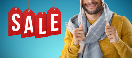 Portrait of smiling man holding wooly hat against abstract blue backgroundの写真素材